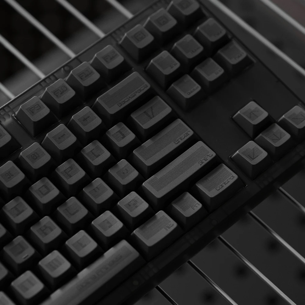 Minimalist black keycap set with futuristic typography and subtle moire patterns.