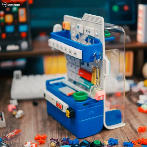 Blue vertical keycap storage case with transparent cover featuring organized white keycaps and miniature accessories on pegboard.
