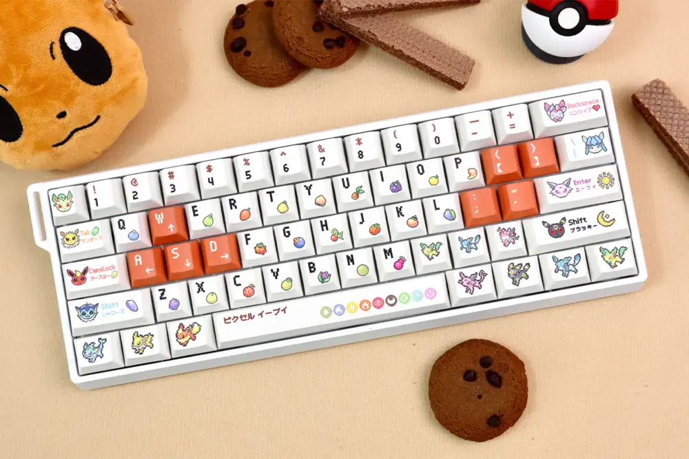 Pokemon Eevee keycaps on 65% white keyboard layout with chocolate cookies and Pokeball, gaming setup aesthetic