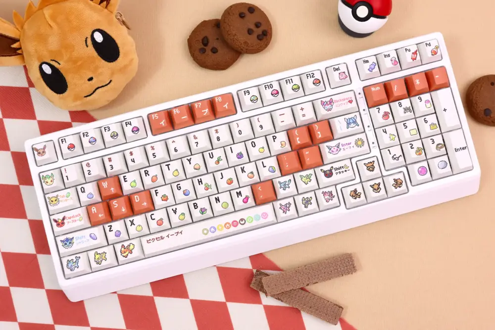 Complete Pokemon Eevee keycaps set on white keyboard with pixel art evolutions, surrounded by Pokeball and Eevee plushie