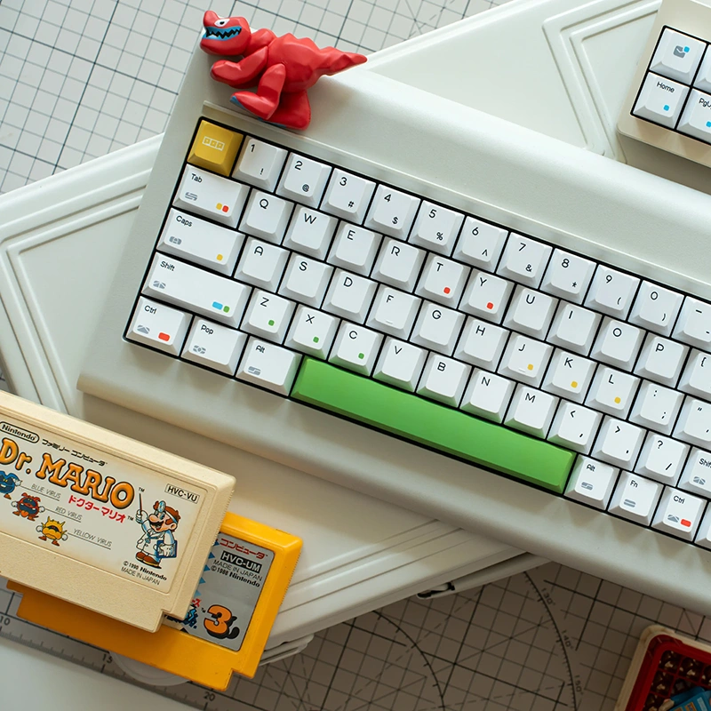 Compact white keyboard featuring green spacebar and colorful dots with gaming collectibles