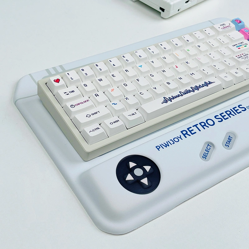 Side view of retro gaming console-styled keyboard wrist rest with d-pad control, supporting a white mechanical keyboard.