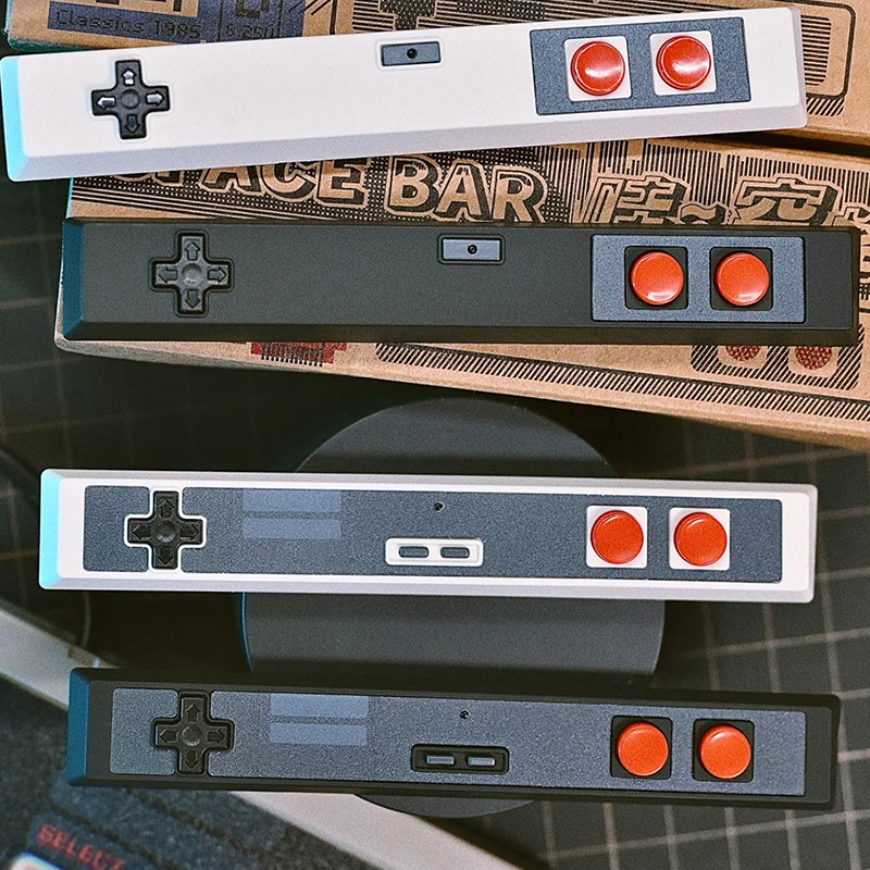 Four controller spacebar keycaps in different colors (white, gray, black variants) displayed together, complete collection