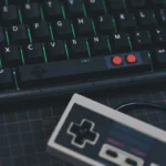 Black controller spacebar on RGB keyboard with green backlighting, retro gaming aesthetic, AB buttons visible
