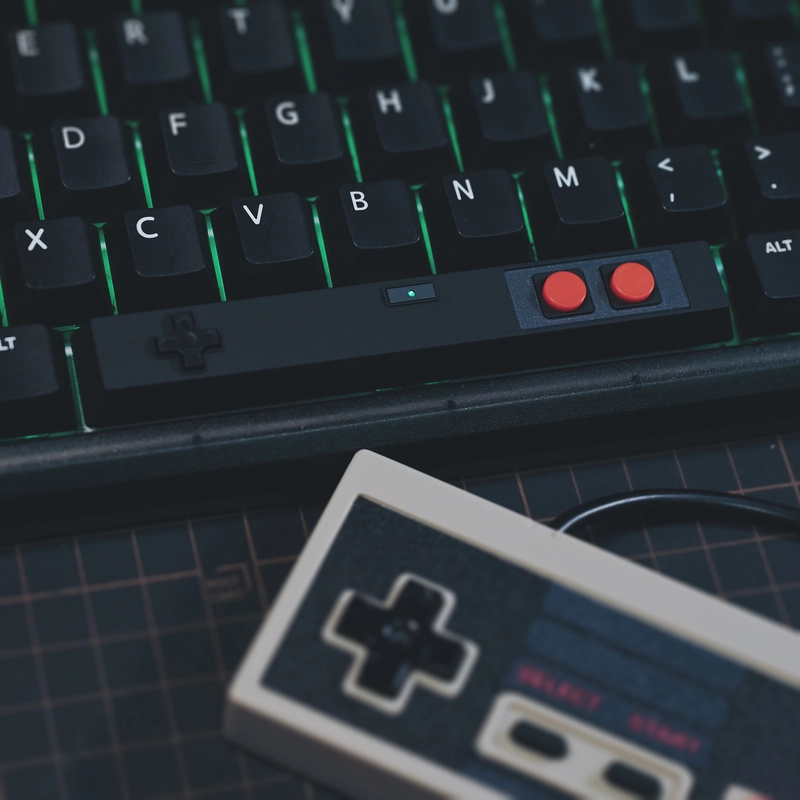 Black controller spacebar on RGB keyboard with green backlighting, retro gaming aesthetic, AB buttons visible