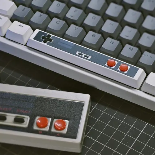 Retro Gaming Spacebar Keycap on a gray mechanical keyboard, showcasing D-pad and red buttons with retro charm.