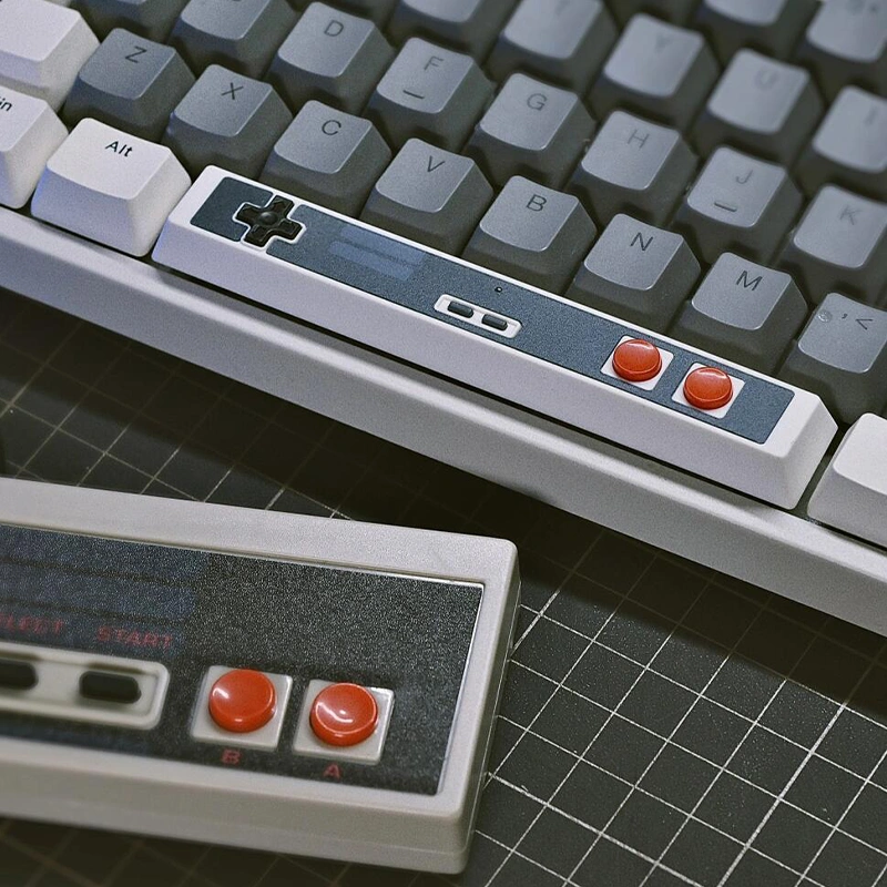 Retro Gaming Spacebar Keycap on a gray mechanical keyboard, showcasing D-pad and red buttons with retro charm.
