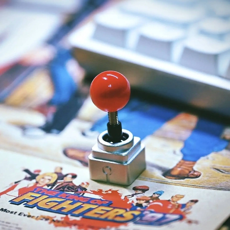 Metal Arcade Joystick Keycap | Retro Gaming Mechanical Keyboard Accessory Metal joystick artisan keycap with red ball top displayed on retro arcade fighting game artwork.