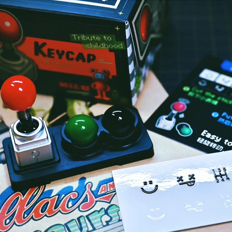 Retro Joystick Metal Artisan Keycap Metal joystick keycap with three colored balls on storage rack, retro gaming magazines, complete accessory set