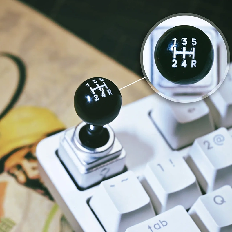 Retro Joystick Metal Artisan Keycap Black joystick ball with white gear shift pattern decal (135-24R) on keyboard, racing theme, automotive design