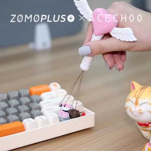 Hand using pink fairy stick keycap puller with wings on mechanical keyboard