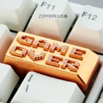 Gold aluminum artisan keycap with Game Over pixel text on white keyboard
