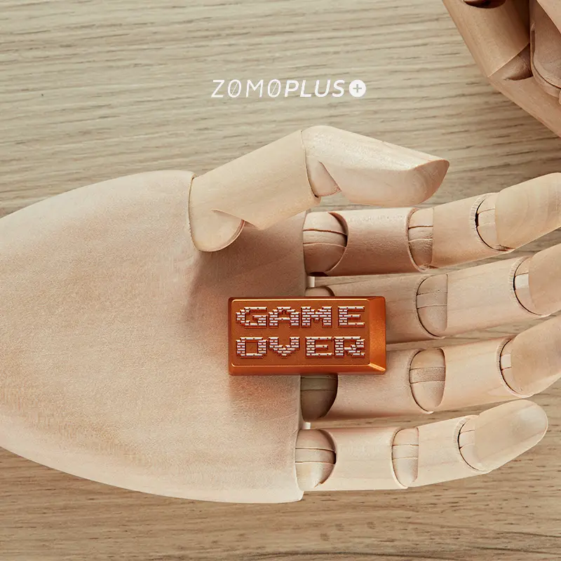 Gold Game Over aluminum artisan keycap displayed on wooden articulated hand sculpture