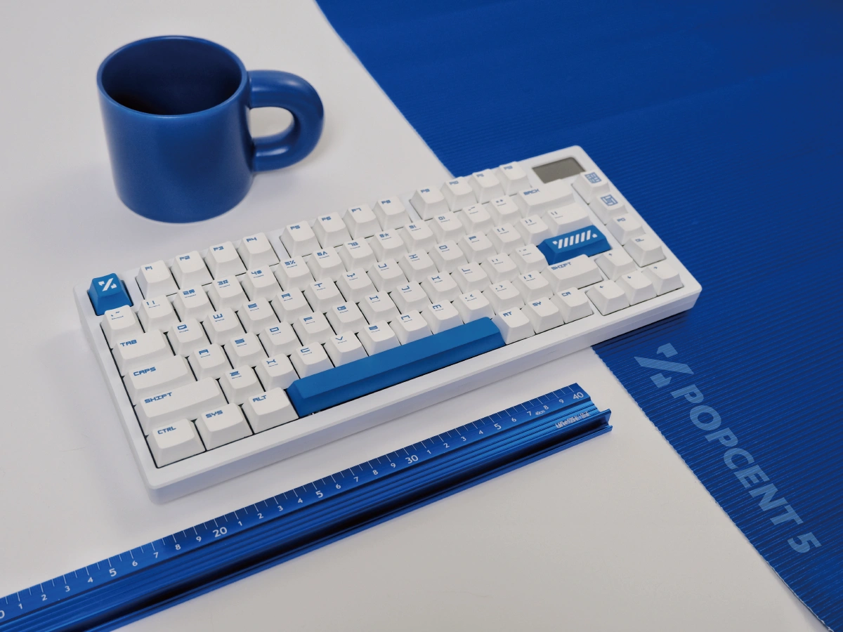 Compact blue keycaps keyboard with ruler and blue mug minimalist workspace flatlay