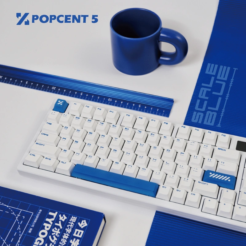 Blue and white mechanical keyboard flatlay with ruler and blue mug setup
