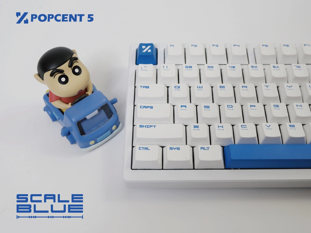 White keyboard with blue accent keycaps next to character figurine closeup detail
