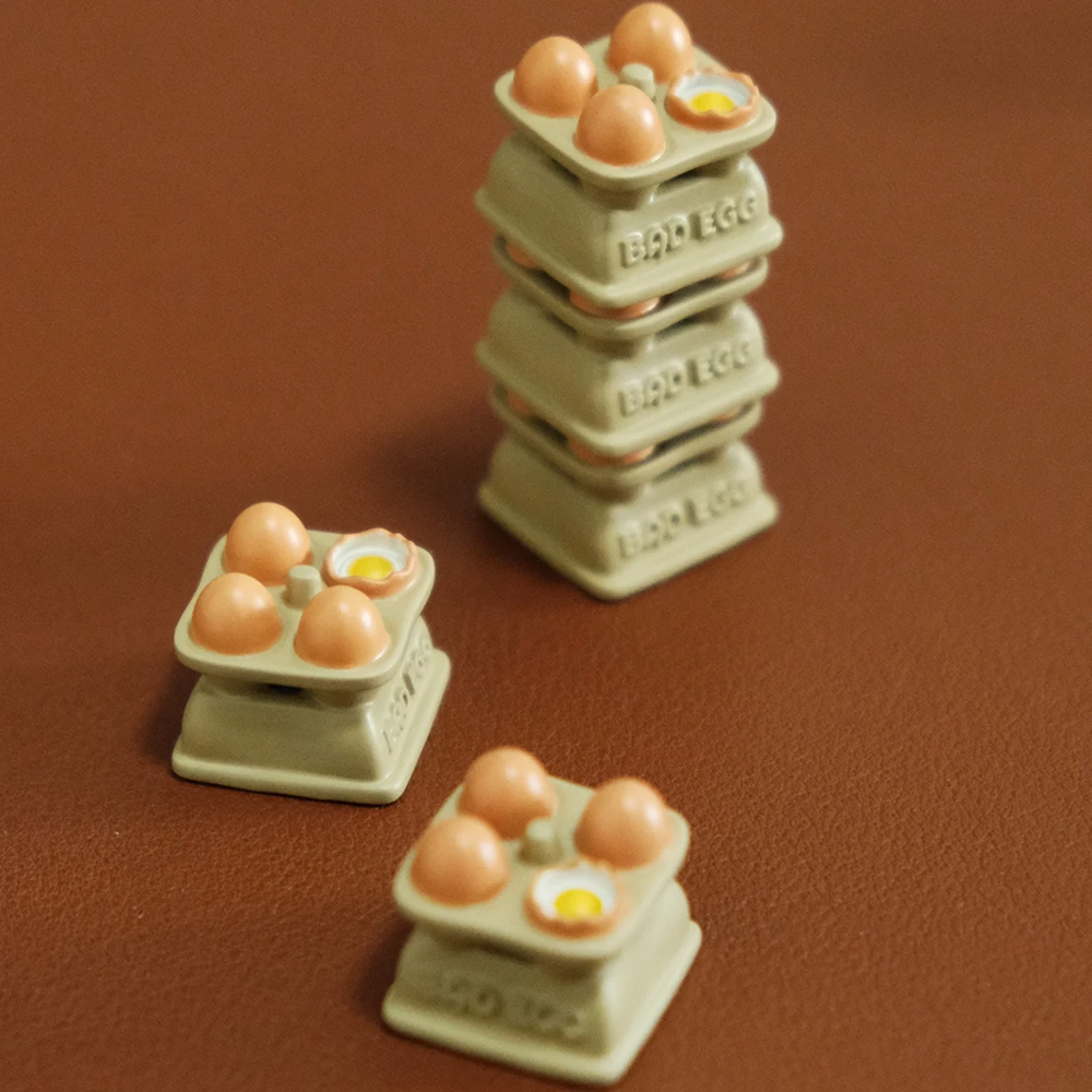 Egg tray 3D printed resin artisan keycaps with hand-painted eggs and yolks on brown background, shown stacked and scattered