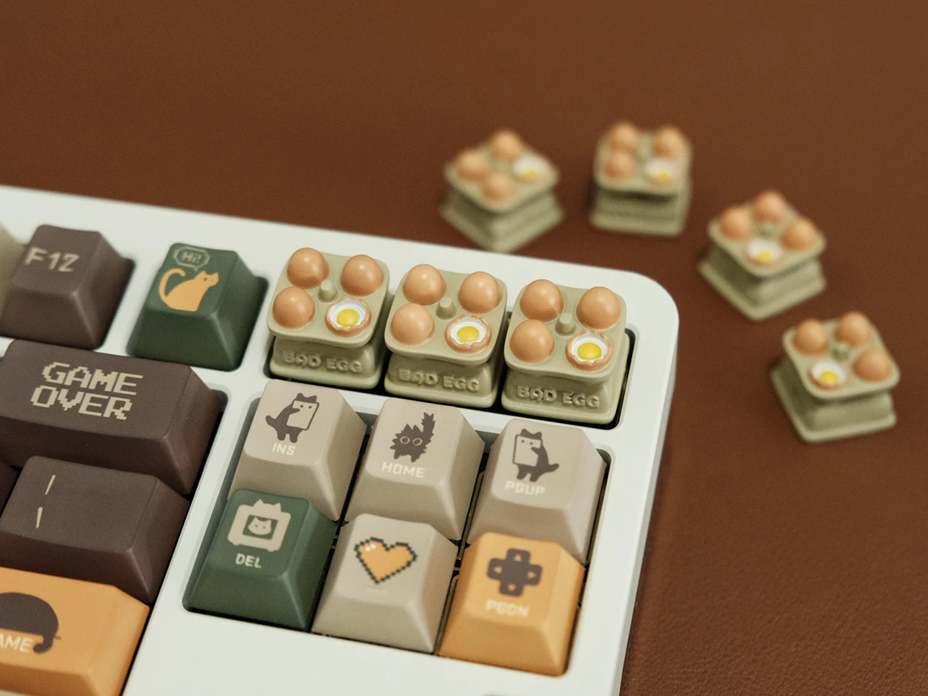 Three egg tray artisan keycaps in a row on white keyboard with additional keycaps scattered behind, showing Bad Egg label detail