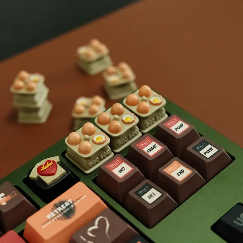 Egg tray artisan keycaps installed on green mechanical keyboard number row with hand-painted eggs, surrounded by extra keycaps