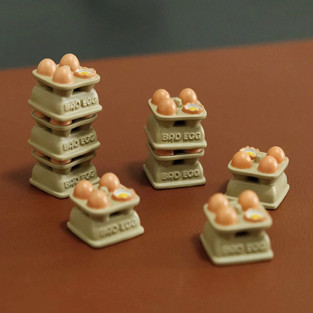 Five stacked egg tray artisan keycaps in varying heights displaying Bad Egg labels and hand-painted eggs with yolk details