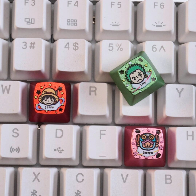 Three ZOMOPLUS One Piece chibi keycaps on mechanical keyboard: red Luffy, green Zoro, and pink Chopper artisan keycaps
