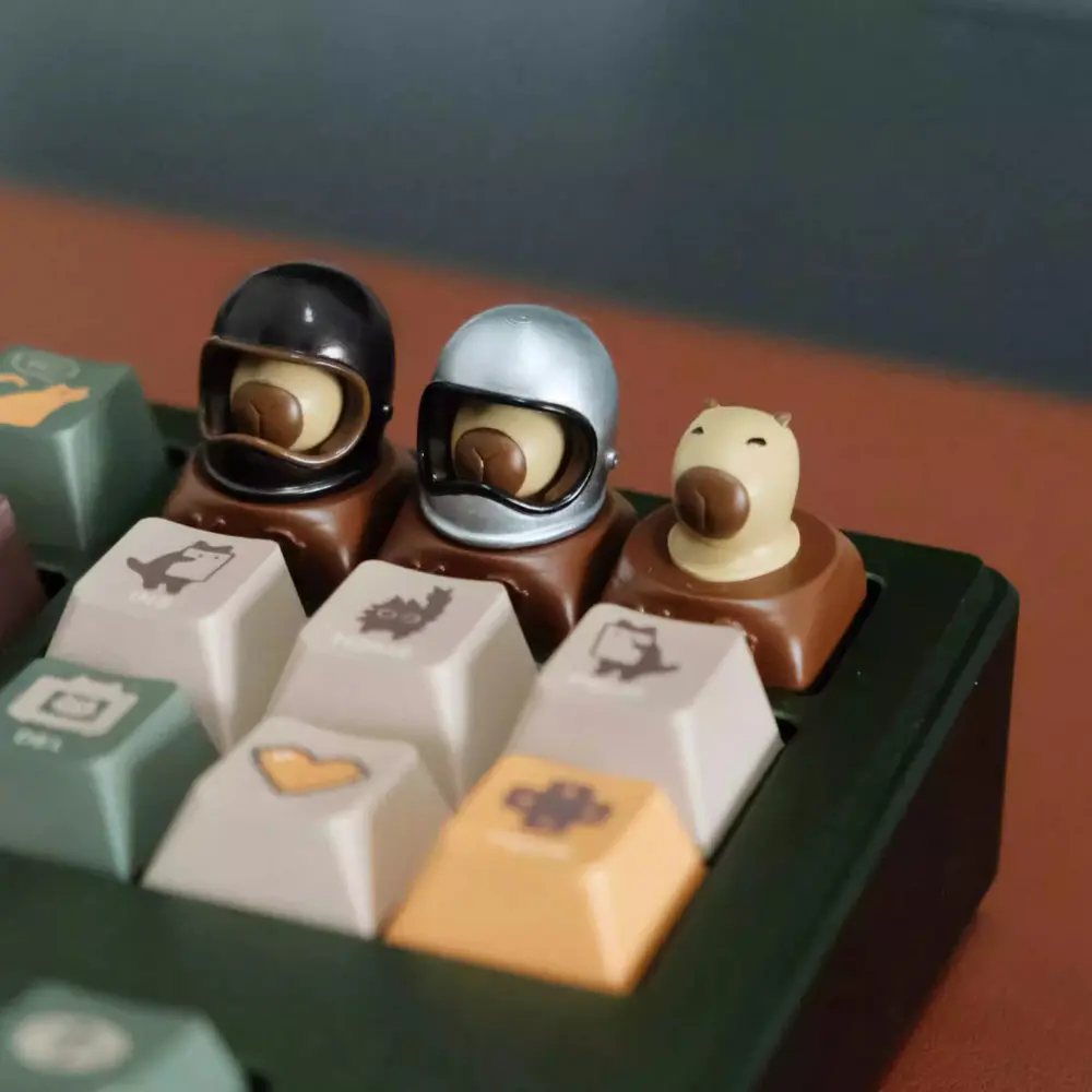 Capybara Artisan Keycaps with Black and Silver Helmets Custom resin keycaps shaped like capybaras featuring detachable magnetic black and silver helmets.