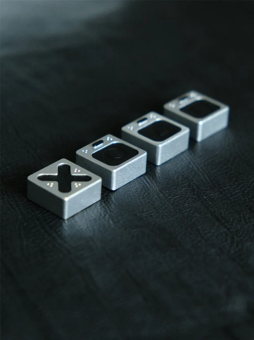Genuine Leather PlayStation Symbols Artisan Keycaps Row of genuine leather PlayStation keycaps with metallic paint finish, focusing on the cross symbol.