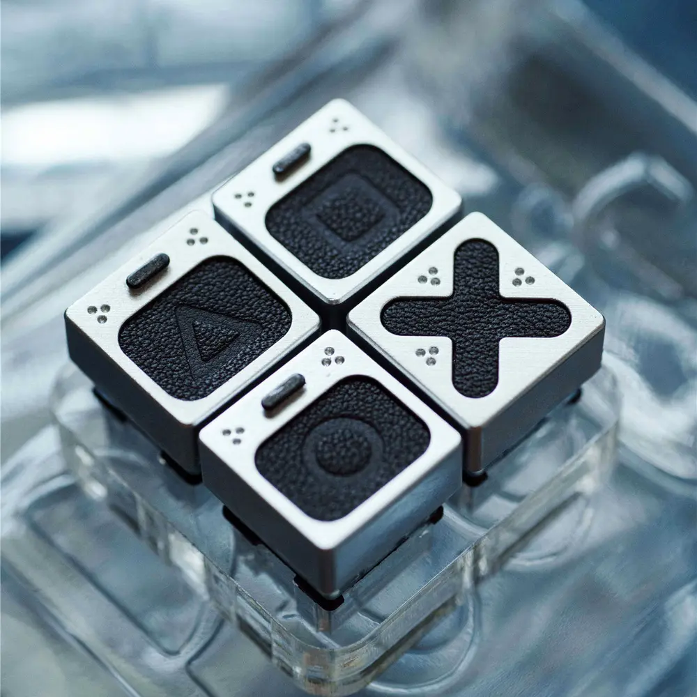 Genuine Leather PlayStation Symbols Keycap Set Four silver and black leather keycaps with Triangle, Circle, X, and Square symbols on a clear base.