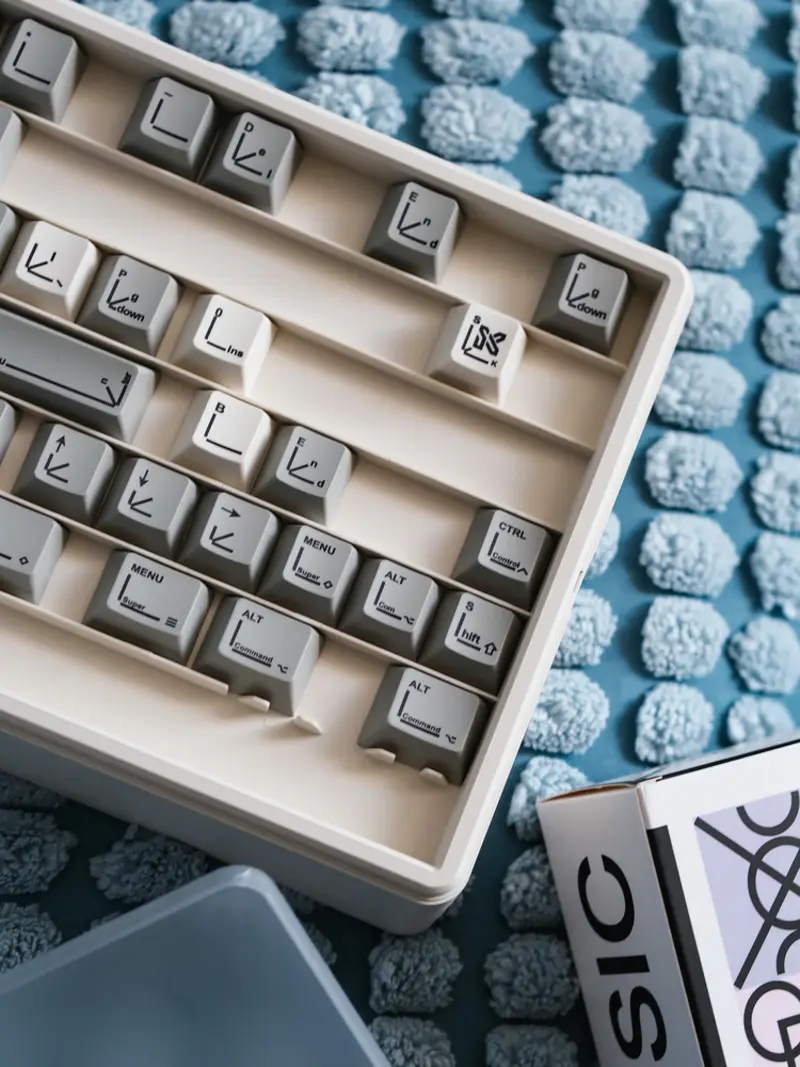 Grey SINOKEY Pastel Retro Design keycaps arranged in a storage tray on a blue textured background.
