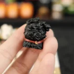 Black 3D printed resin puppy keycap with wind-blown fur design and red collar held in hand.