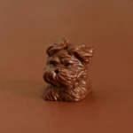 Close-up of a cute puppy keycap in coffee brown resin featuring textured wind-swept fur details.