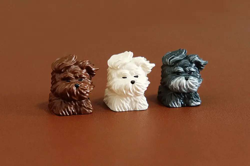Trio of cute wind-blown puppy artisan keycaps in brown, white, and black resin.