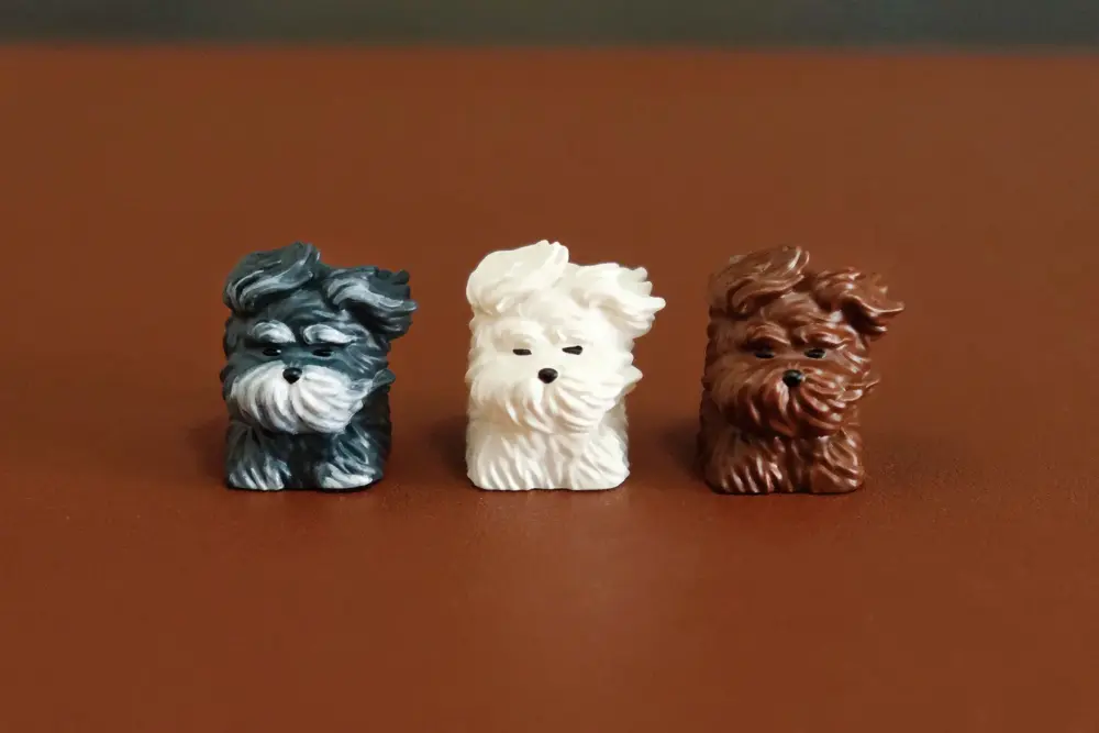 Trio of cute puppy resin keycaps featuring wind-swept fur designs in grey, white, and brown.