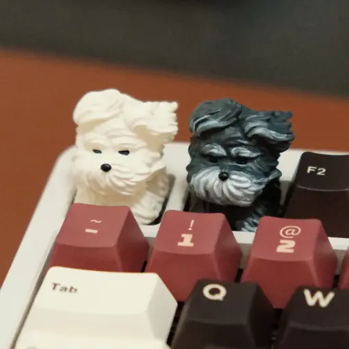 Side-by-side view of white and black 3D printed resin puppy keycaps with wind-swept details.