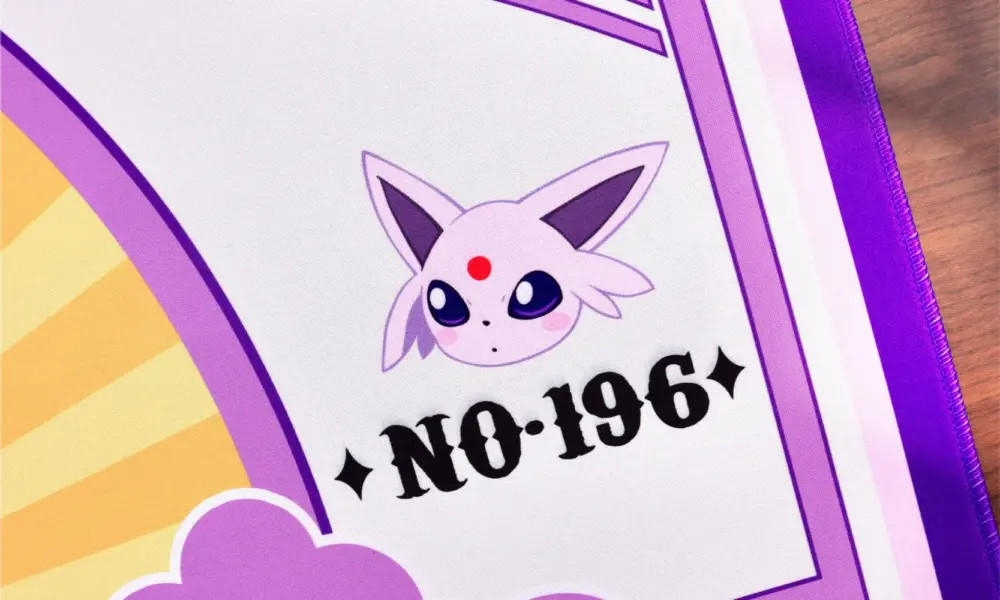 Detail shot of Pokemon Espeon gaming mat with character face and number 196 graphic.