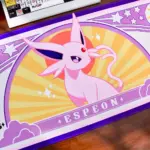 Pokemon Espeon large gaming desk mat on a desk next to a mechanical keyboard and figures.