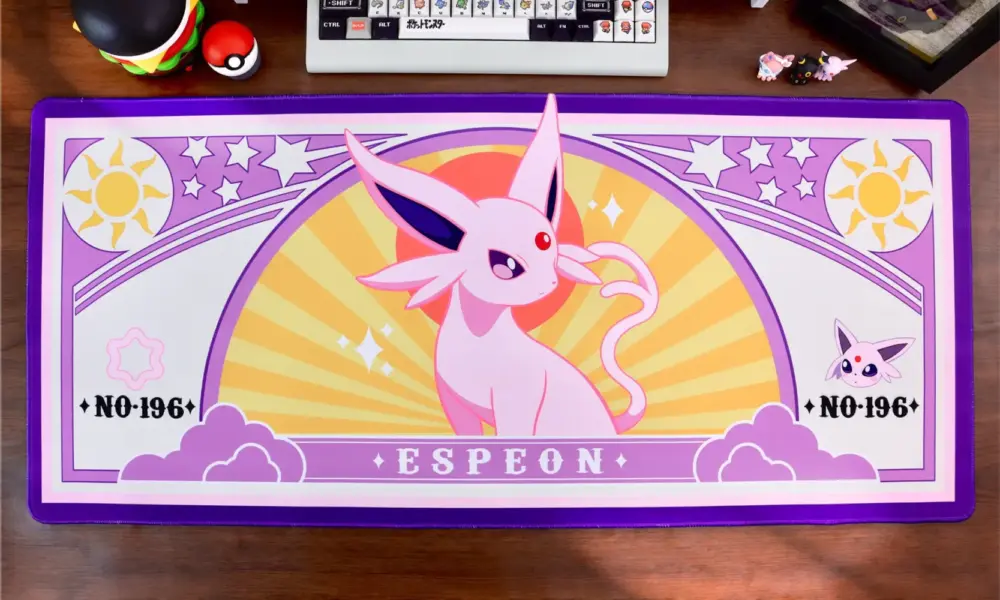 Espeon gaming desk mat with pink and purple art nouveau design on a wooden desk setup.