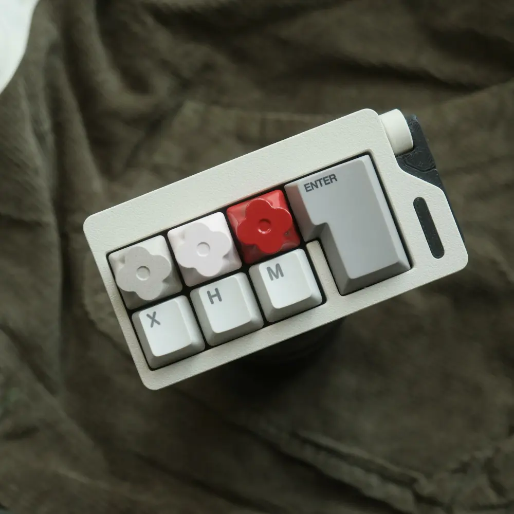 Top-down view of three flower-shaped aluminum keycaps in different colors next to an ISO enter key.