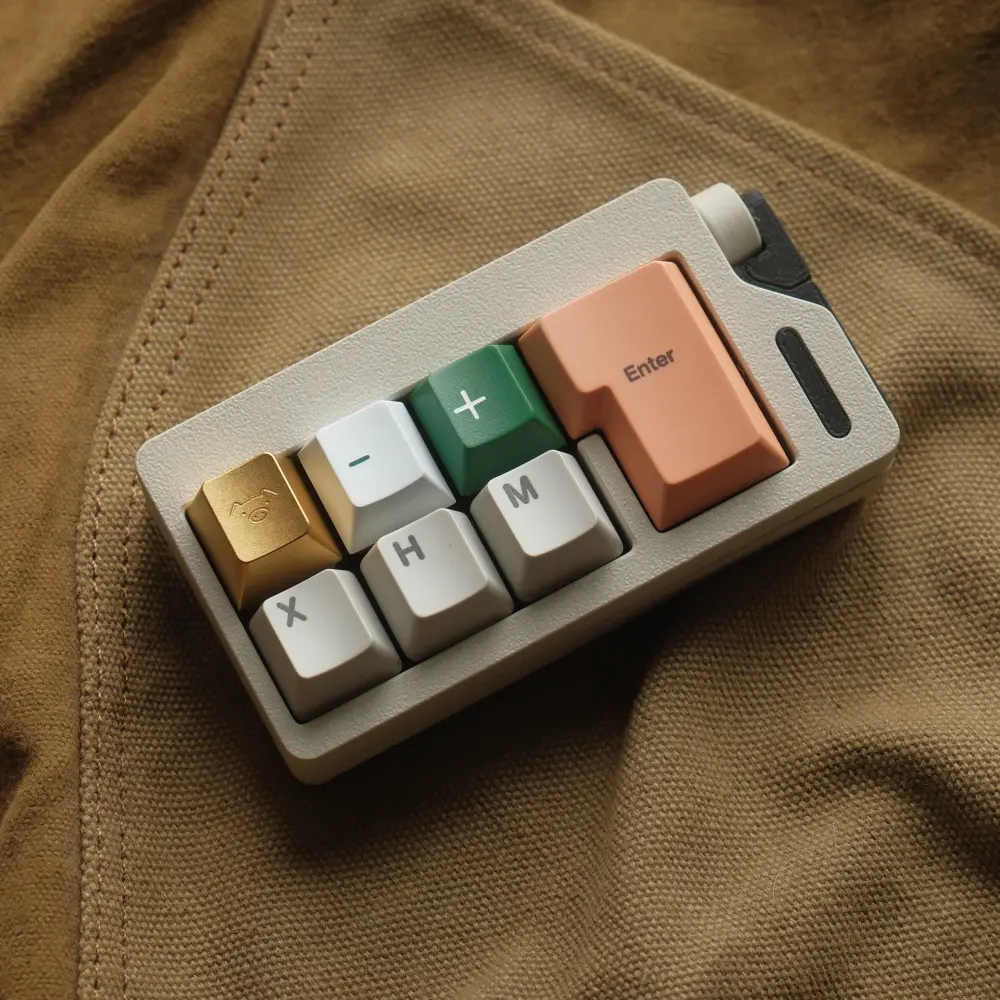 Champagne gold metal artisan keycap with a minimalist pig engraving mounted on a small gray macropad.