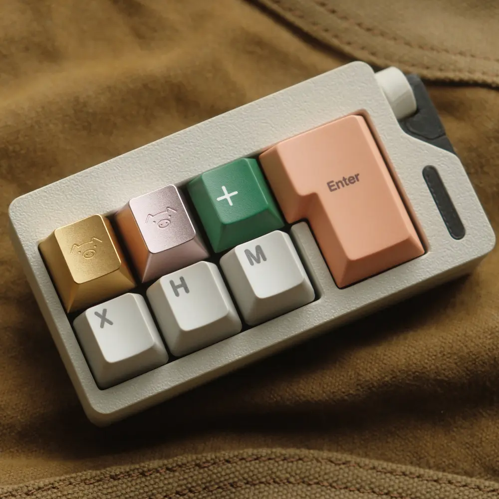 Gold and pink metal artisan keycaps with engraved pig faces on a white keyboard with colorful keys.