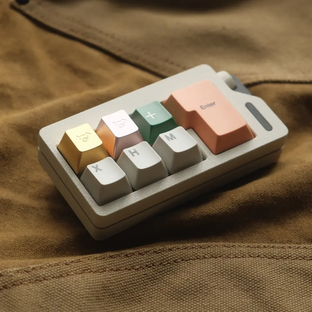 Close-up of champagne gold and blush pink metal artisan keycaps with pig engravings on a small keypad.