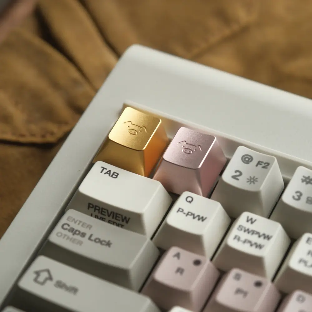 Gold and pink metal artisan keycaps with engraved pig characters on a mechanical keyboard.
