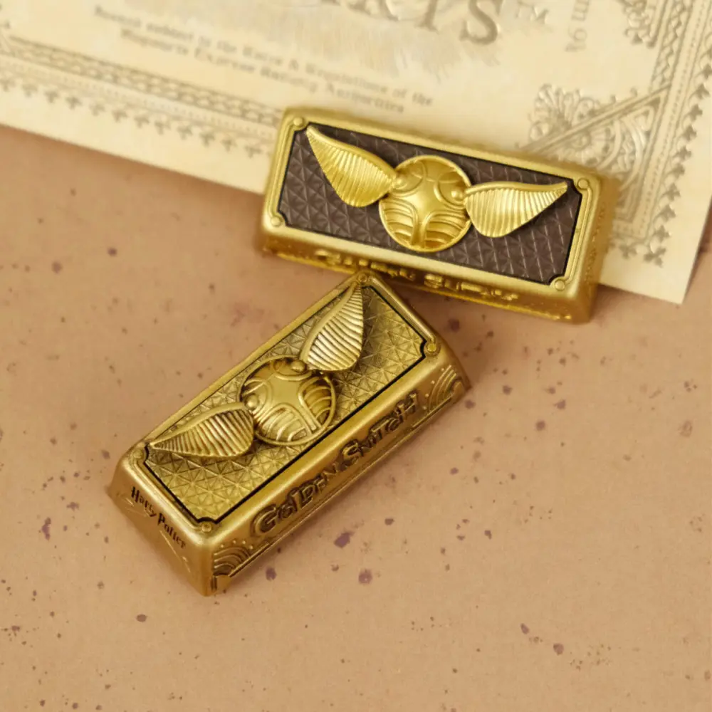 Two Harry Potter Golden Snitch artisan keycaps showcasing the vintage oxidized and dual-color finish options.