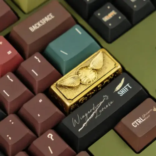 Close-up of the vintage oxidized Harry Potter artisan keycap featuring a 3D Golden Snitch design on a keyboard.