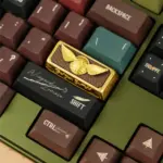 Gold-painted Harry Potter artisan keycap with a Snitch design mounted on a mechanical keyboard.
