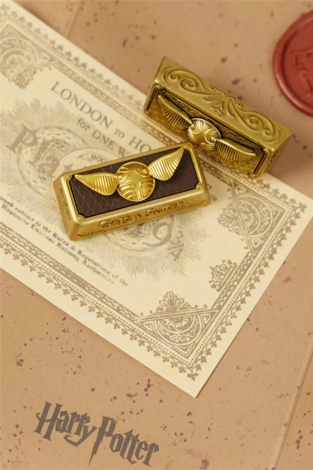 Close-up of two golden snitch artisan keycaps featuring intricate wings and gold detailing for mechanical keyboards.