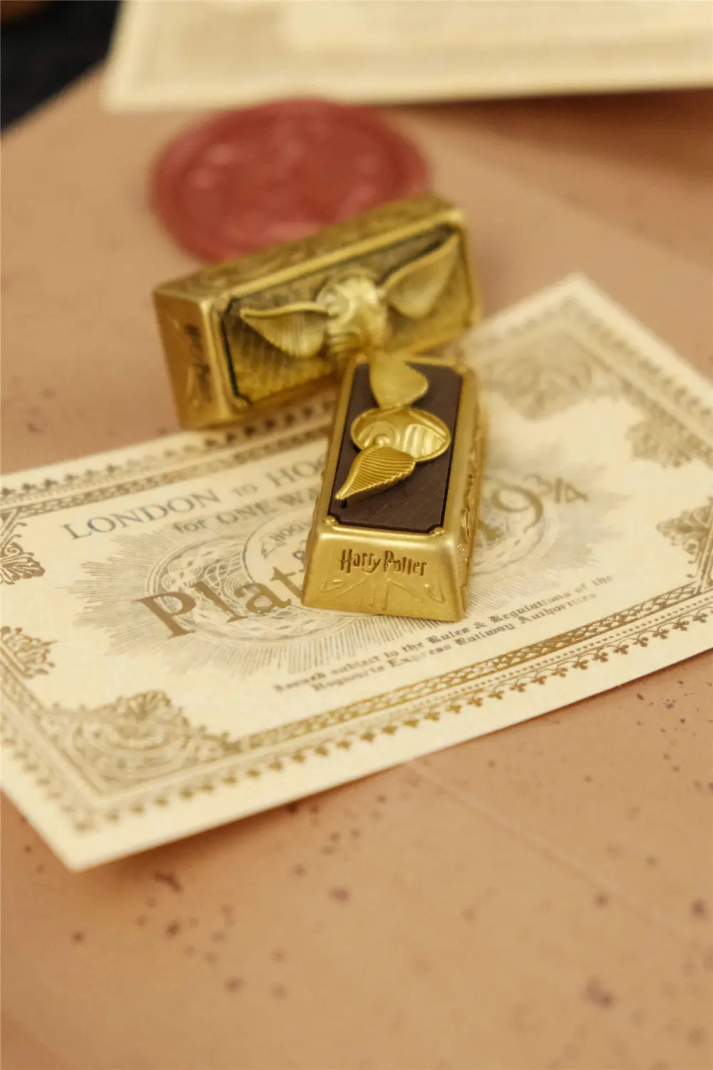 Golden Snitch artisan keycap with a vintage oxidized finish on a London to Hogwarts train ticket.