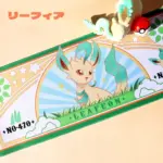Pokemon Leafeon large gaming desk mat showcasing stylized character art with a plush toy and Pokéball on the surface.