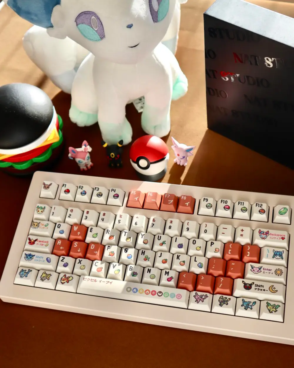 Assembled mechanical keyboard with Pokemon Eevee pixel keycaps, a Pokeball, and Eeveelution toys.