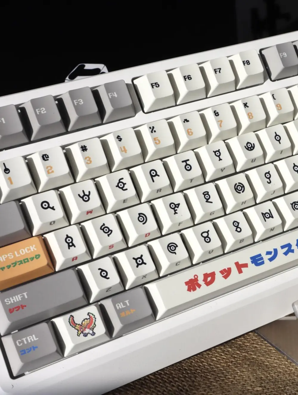 Pokemon Unown Keycaps Close Up Pokemon Unown keycaps on a keyboard featuring a Ho-Oh novelty key and Japanese text on the spacebar.